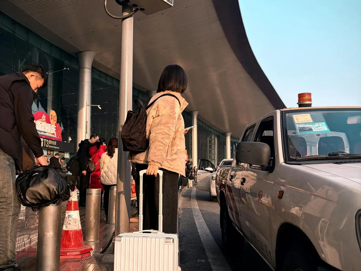 International traveler waiting at a China airport pickup area with luggage