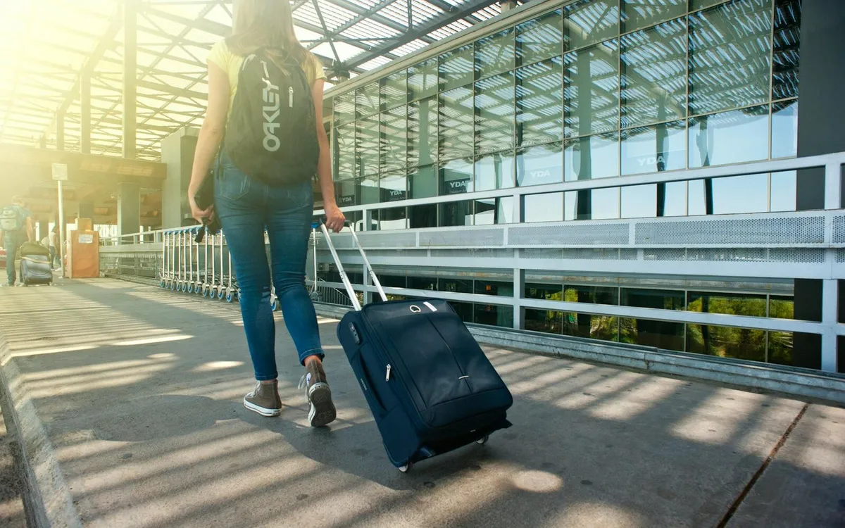 Traveler walking through an airport terminal with luggage before arrival support begins
