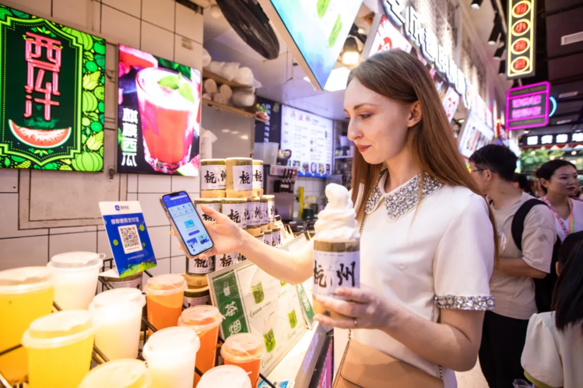 Traveler scanning a mobile payment QR code at a food stall in China