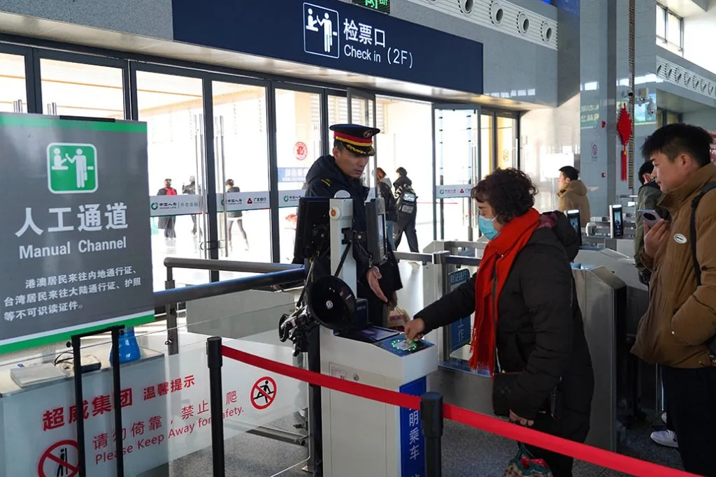 Passengers using a manual ticket check channel at a China railway station