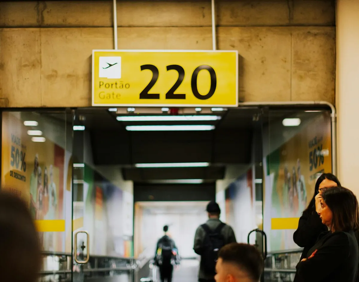 Airport gate sign and passengers waiting during a possible flight change