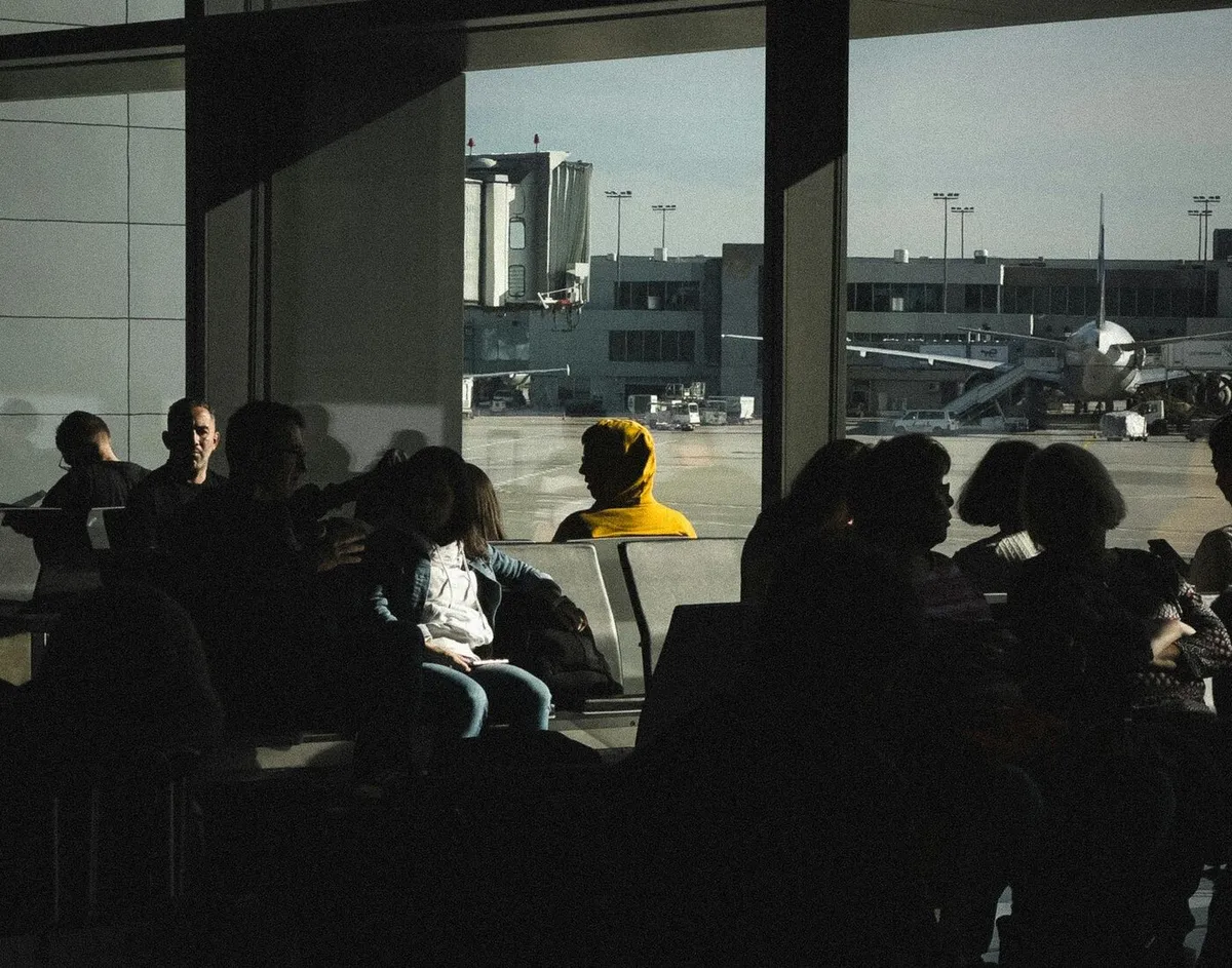 Passengers waiting near an airport window after a delayed flight announcement