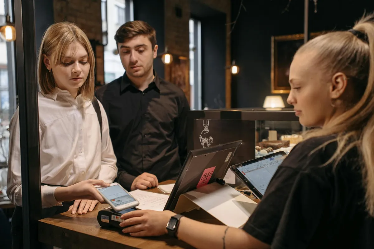 Travelers testing a phone payment at a cafe counter before relying on mobile payment in China