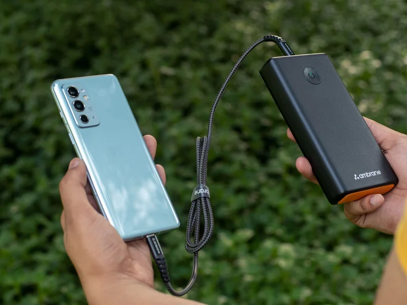 Traveler holding a phone and portable power bank during an outdoor travel day