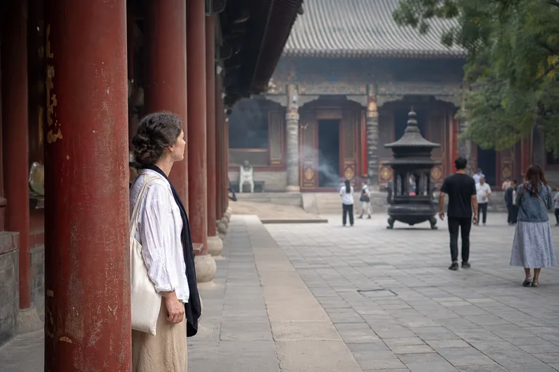 Visitor standing quietly at the side of a traditional Chinese temple courtyard