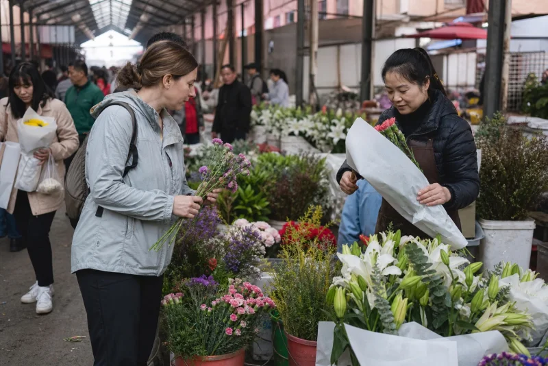 Florist wrapping flowers at a Chinese market while visitors browse